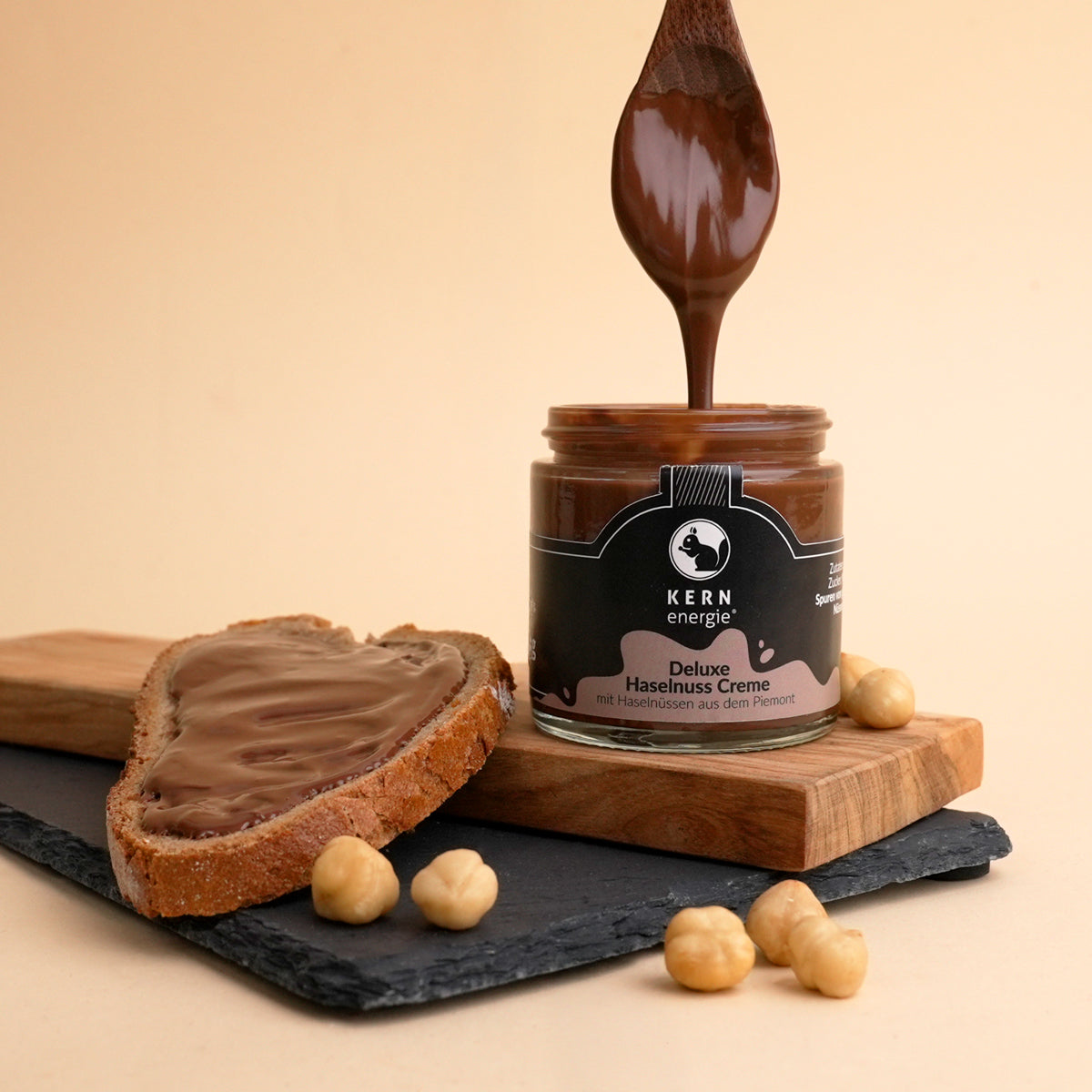 Stimmungsbild der Deluxe Haselnuss Creme mit Creme auf einem Löffel und auf einem Brot