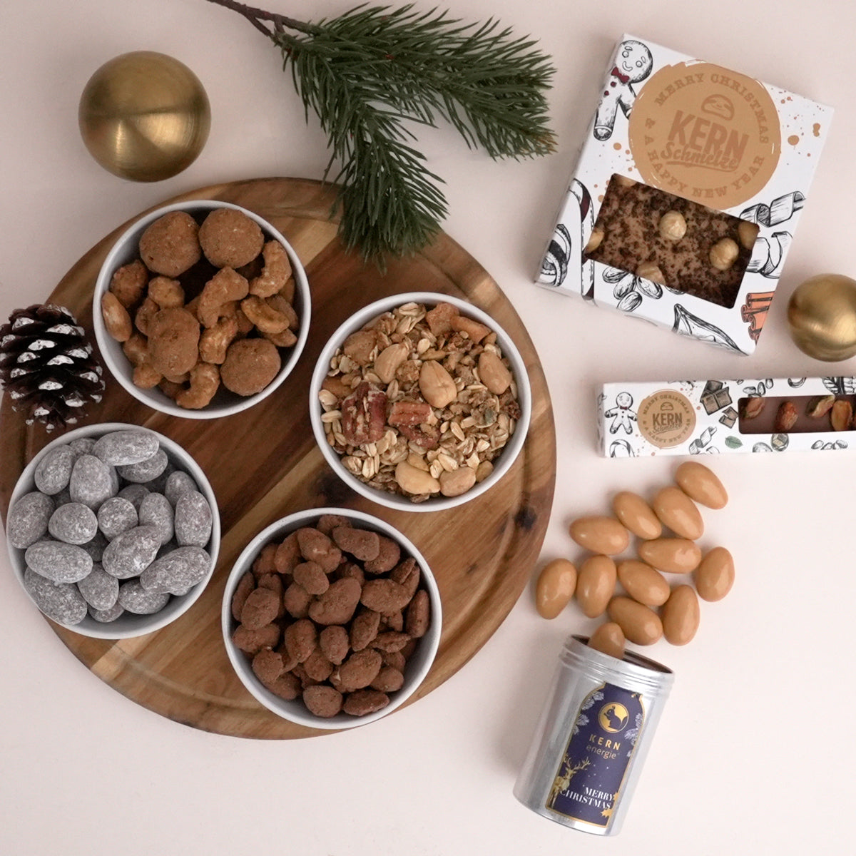 Müsli, gebrannte Nüsse und Schokolade in weihnachtlichen Verpackungen und Schalen serviert