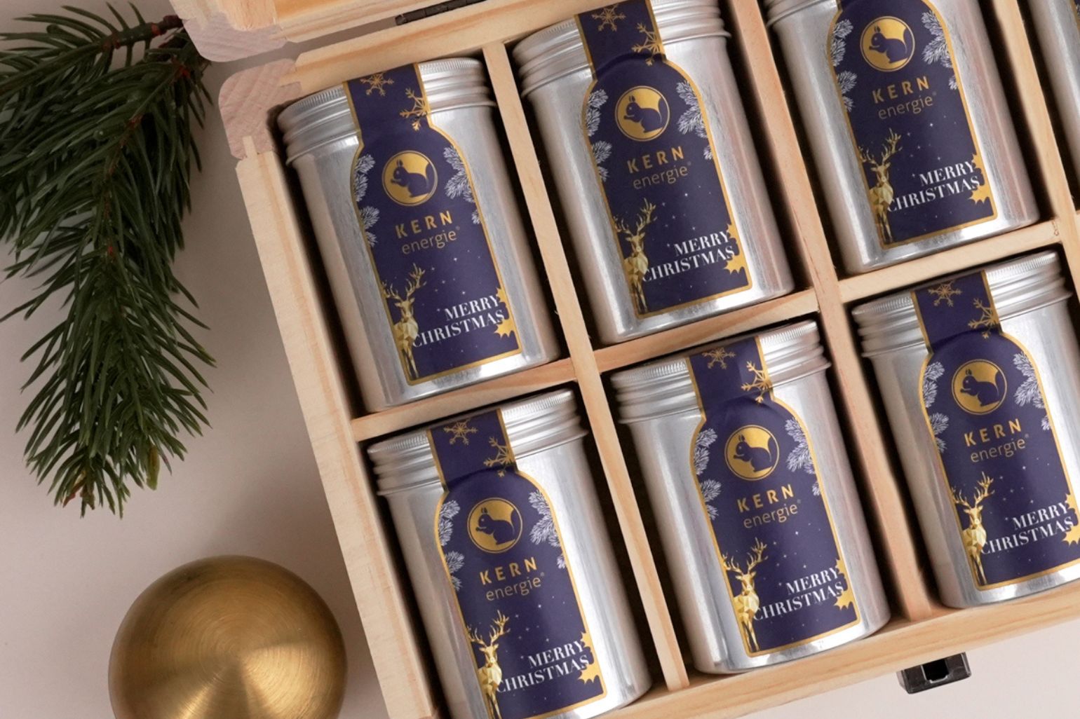 Nahaufnahme einer personalisierten Holzbox mit Nüssen in Aludosen im exklusiven Weihnachtsdesign 2025 – hochwertige weihnachtliche Werbegeschenke für Firmenkunden.