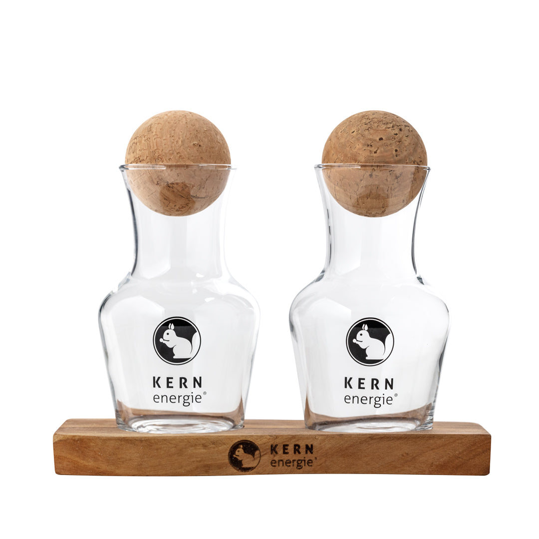 Zwei edle KERNenergie Glas-Dekanter auf einem Holztablett, minimalistisches Design.