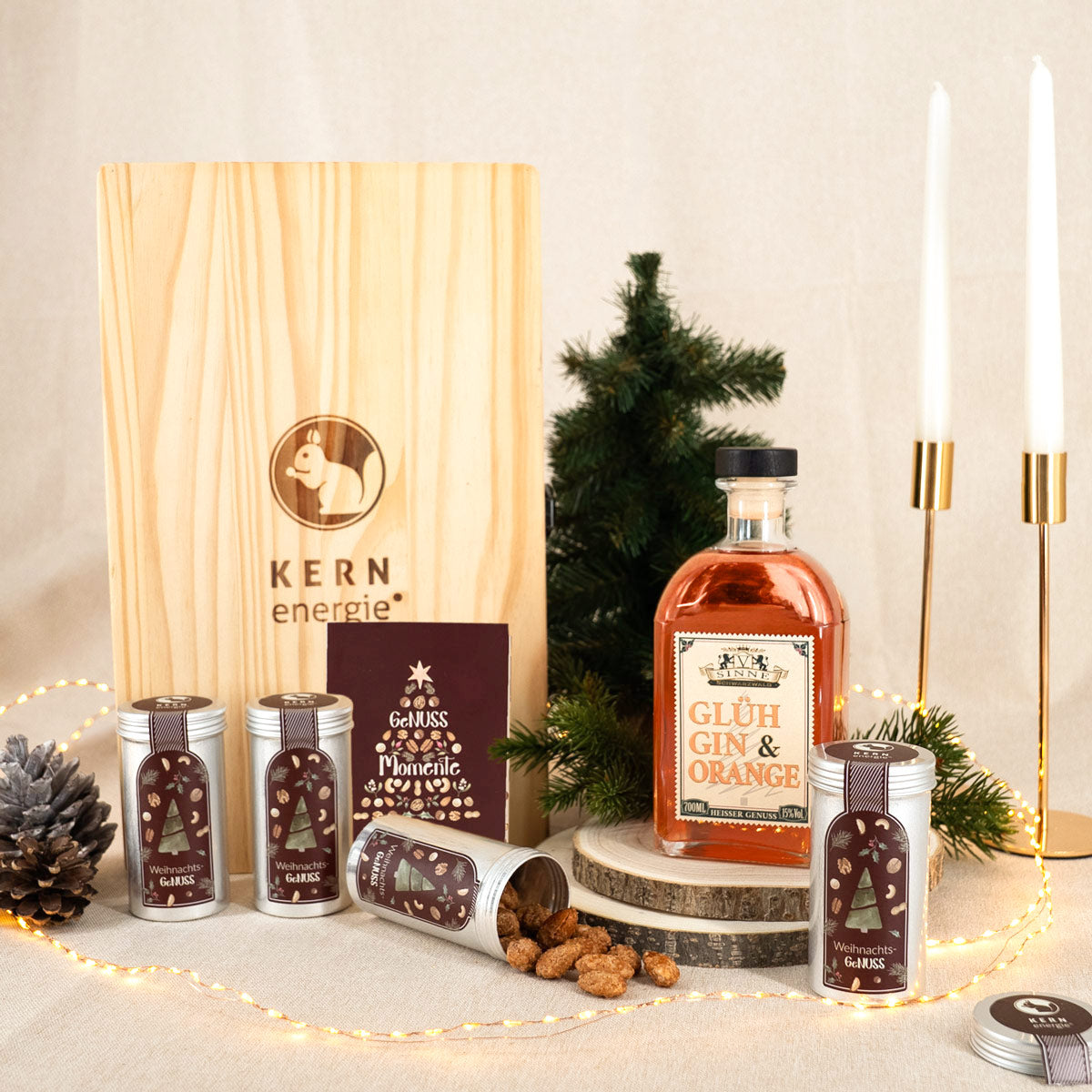 verschiedene Nüsse in weihnachtlichen Aludosen und ein Glüh Gin vor einer Holzbox