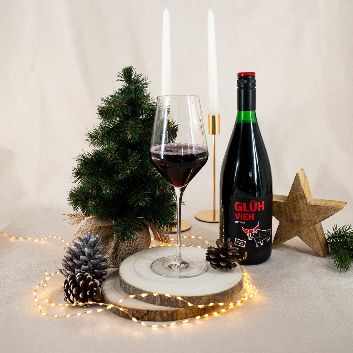 Befülltes Glas mit rotem Glühwein "Glüh Vieh" von Metzger mit weihnachtlicher Dekoration