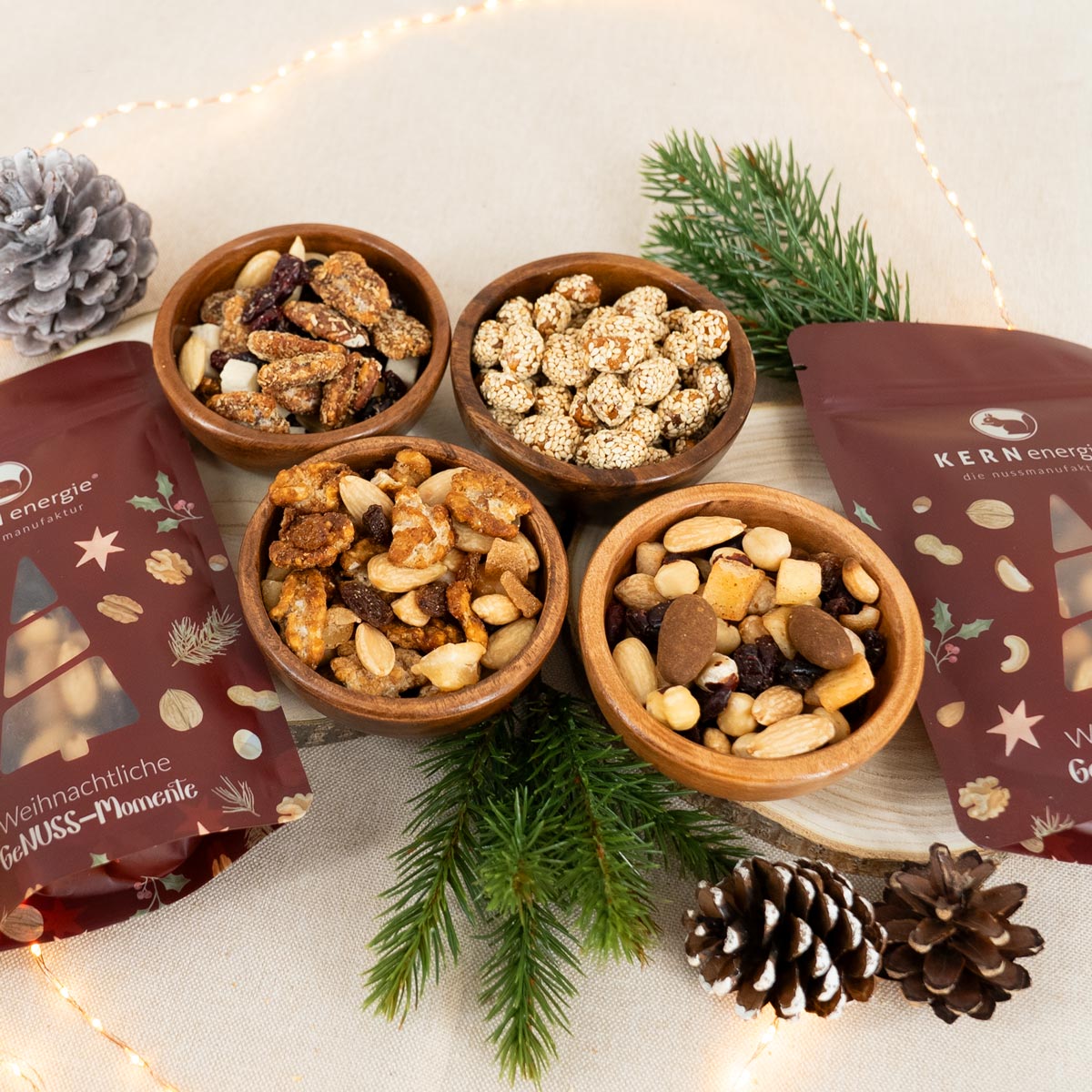 Nussmischungen und gebrannte Nüsse in Holzschalen mit weihnachtlichen Snackbeuteln