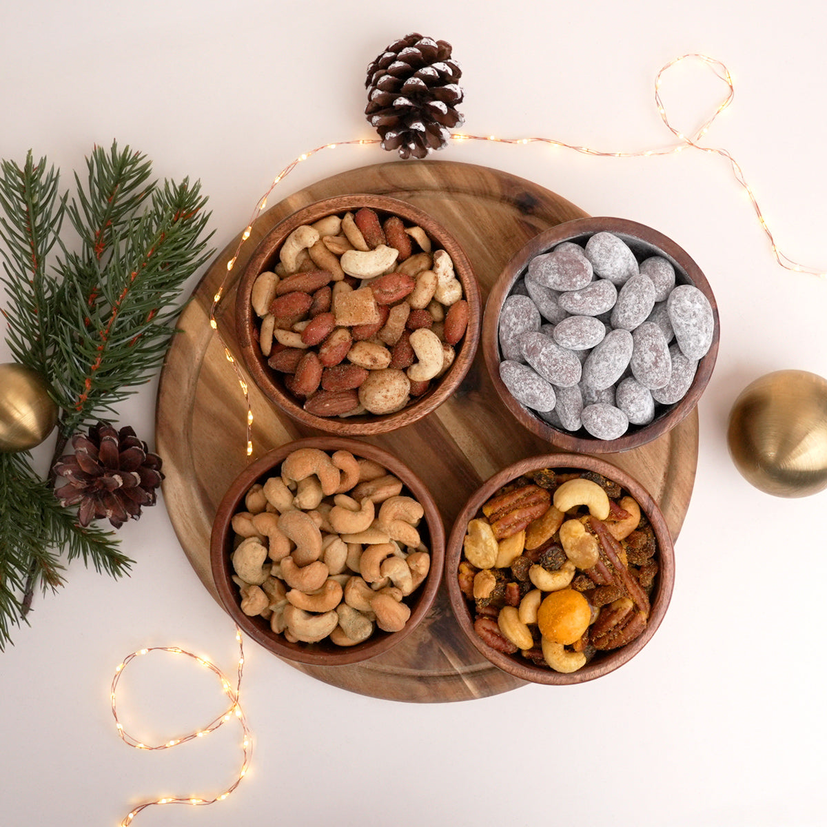 Cashews, zwei Nussmischungen und schokolierte Mandeln in Holzschalen