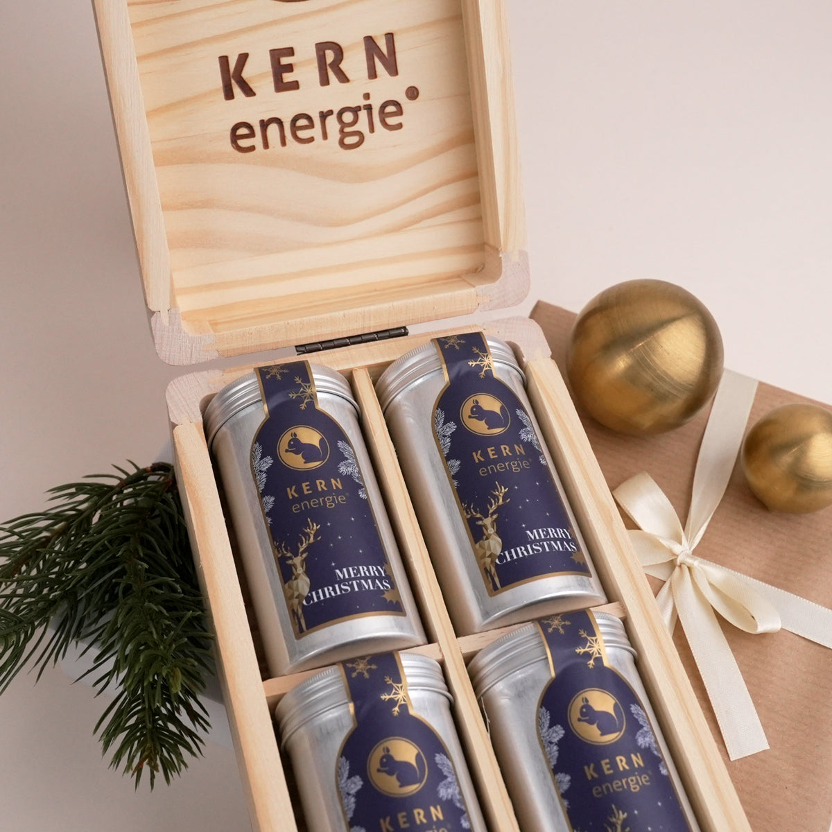 vier Aludosen mit Weihnachtsetikett in einer Holzbox