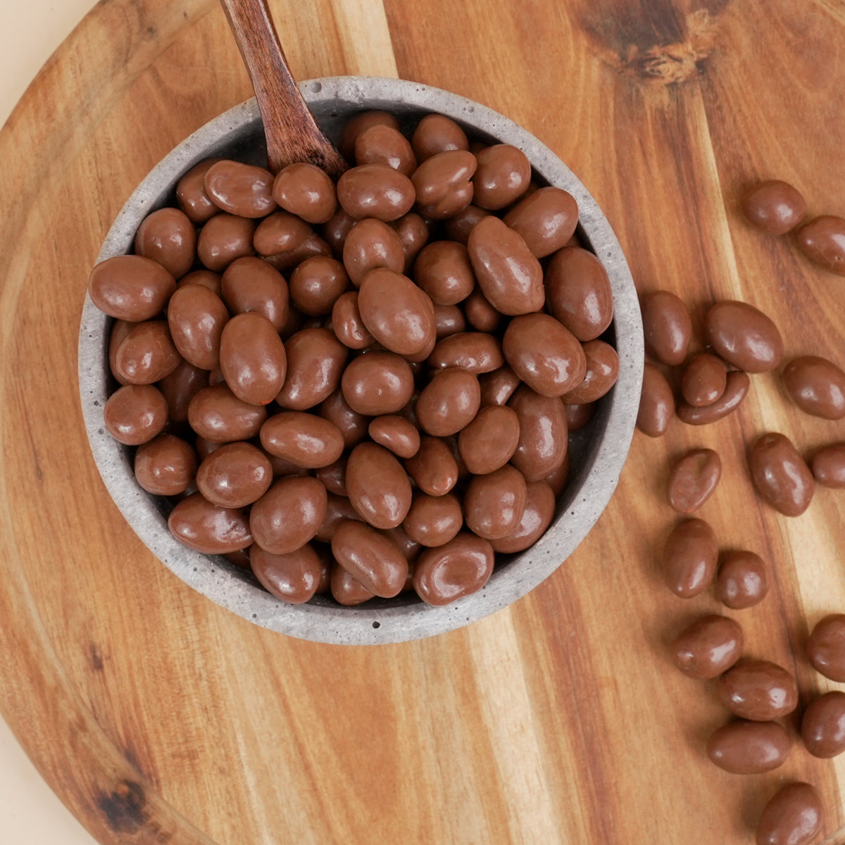 Schüssel mit Vollmilch schokolierten Erdnüssen auf Holzgrund