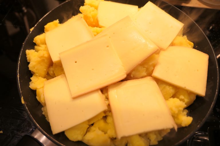 Käse auf Kartoffel Pfanne verteilen