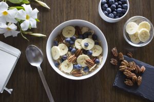 Frühstücksbowl mit Müsli, Bananen, Blaubeeren und Pekannüssen